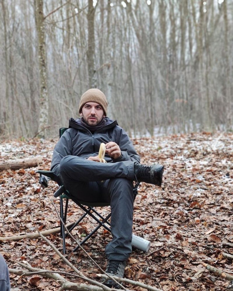 Tunca sitting on a camp chair in a winter forest